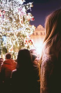 Person looking up at decorated outdoor Christmas tree