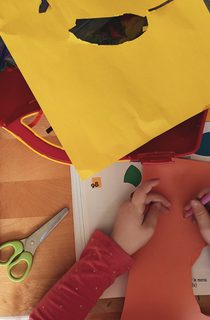 A child surrounded by bright cardboard at a craft table