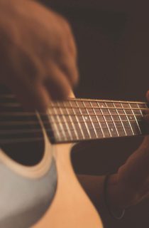 Person playing acoustic guitar with a capo