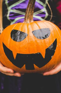Girl in witch costume holding a smiling pumpkin