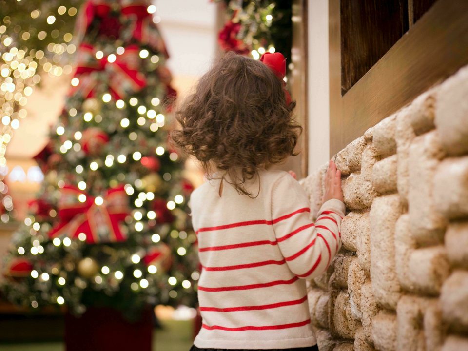 Brown haired child looking at decorated Christmas tree