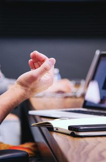 Person with laptop, notebook and phone on table in front of them