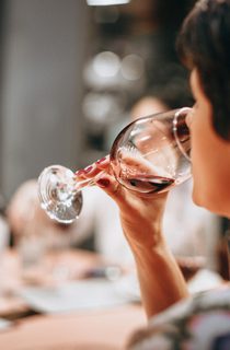 A person drinking from a clear wine glass
